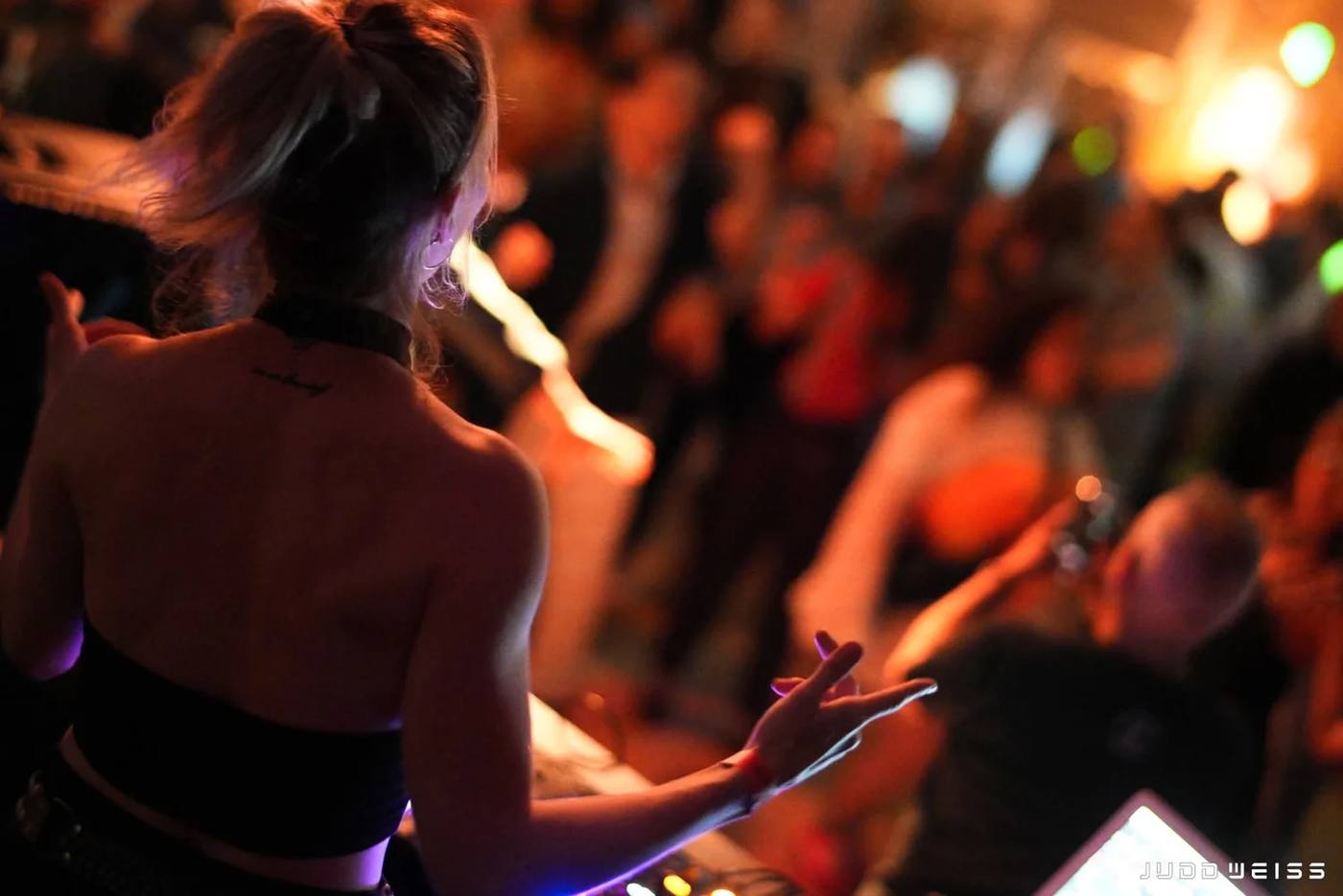 A performer at the keys, lit in warm stage light, facing a crowd.